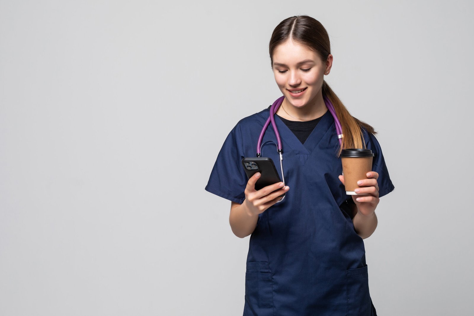 Female doctor sitting with mobile phone and drinking coffee